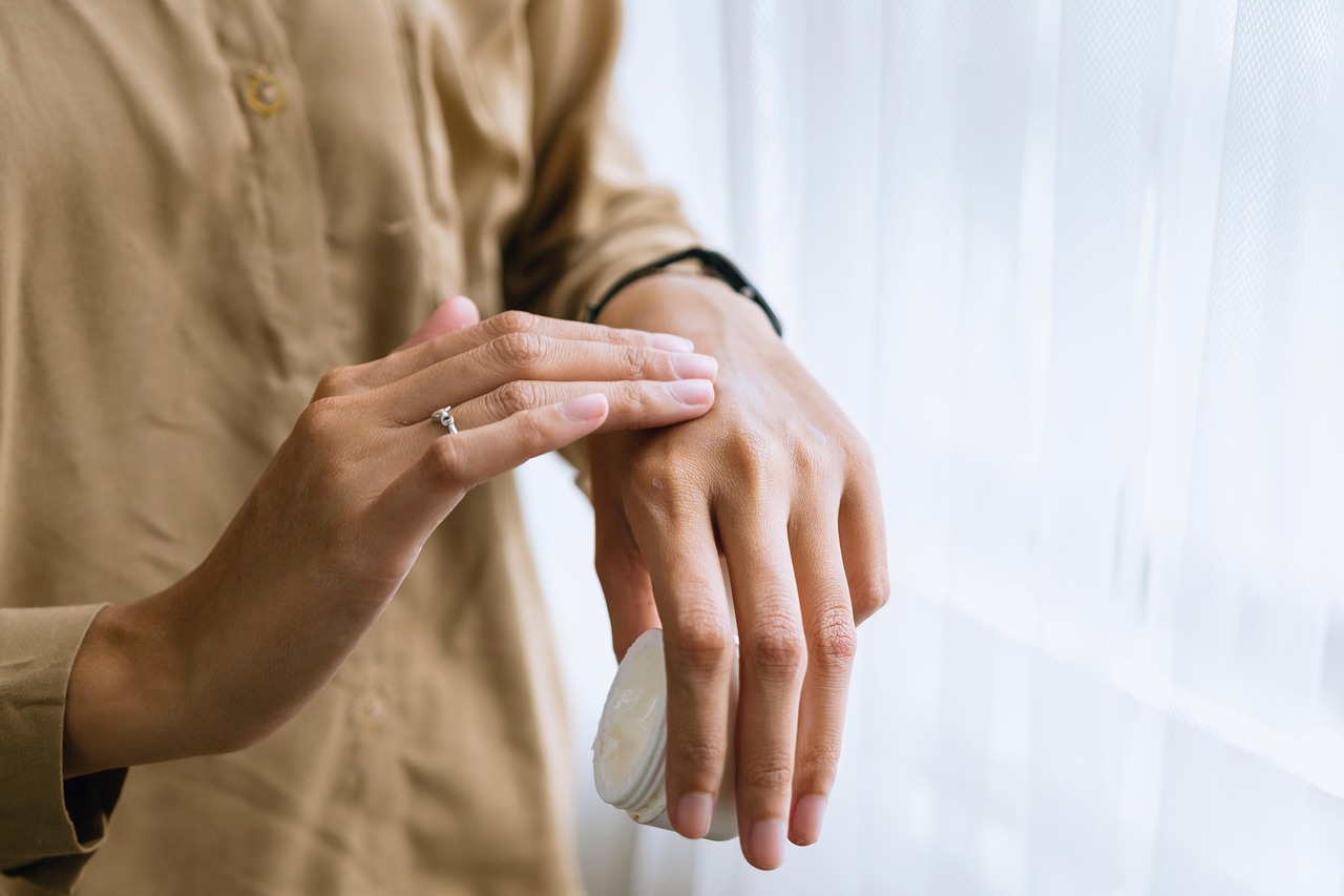 A person smoothing white cream onto the back of one hand